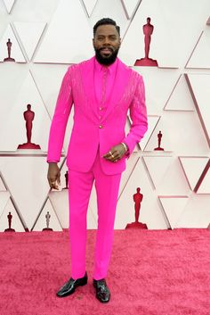 a man in a pink suit and black shoes on the red carpet at an oscars