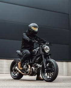 a man riding on the back of a motorcycle wearing a helmet and black leather pants