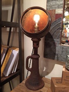 an old fashioned table lamp on top of a wooden table next to boxes and other items