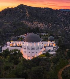 an aerial view of a white building with domes on top at sunset in the mountains