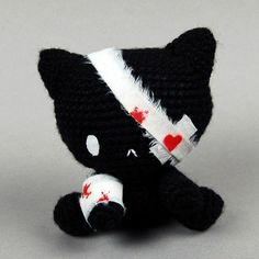 a small black and white stuffed animal with blood on it's face, sitting in front of a gray background