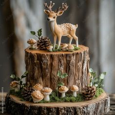 a cake decorated with mushrooms and deer figurines on a tree stump in the woods