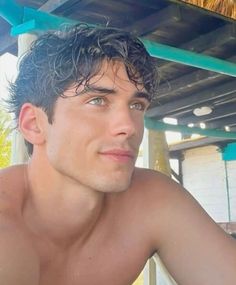 a man with no shirt on sitting under a roof