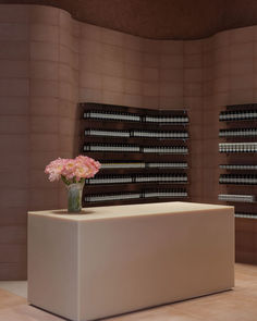 a vase filled with pink flowers sitting on top of a white counter next to shelves