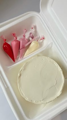 a plastic container filled with white frosting next to two red hearts