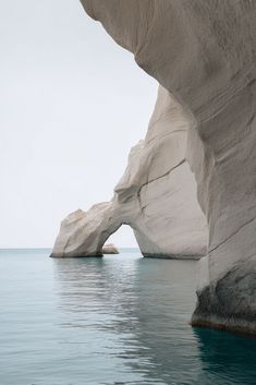 a large rock formation in the middle of water with an arch sticking out of it