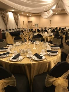 a banquet hall with tables and chairs covered in gold cloths, black napkins and place settings