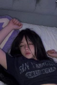 a woman laying on top of a bed next to a pillow