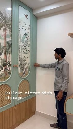 a man standing in front of a green cabinet with tropical designs on the glass doors