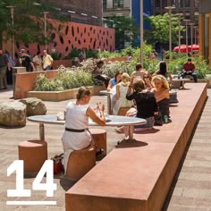 people are sitting at tables in the middle of a public park with plants and flowers