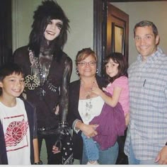 a group of people standing next to each other in front of a mirror with an image of a woman on it