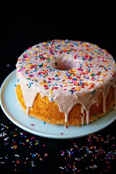 a cake with white frosting and sprinkles on a blue plate next to a black background