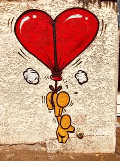 a red heart shaped balloon being held by a sticker on the side of a building