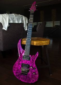 a purple guitar sitting on top of a hard wood floor