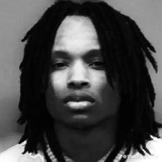 a black and white photo of a man with dreadlocks wearing a shirt on