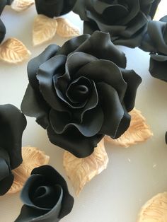 some black roses are on a white table and one is in the middle of it
