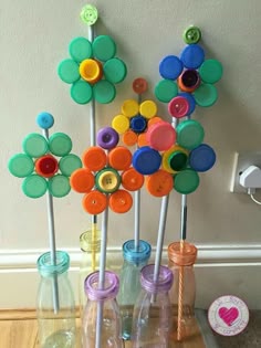 there are many colorful plastic flowers in the bottles on the table and one is made out of buttons