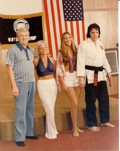 two men and three women posing for a photo in front of an american flag