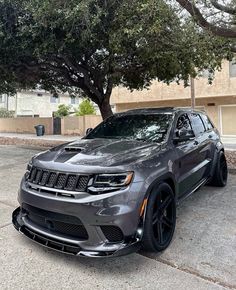 a grey jeep parked in front of a tree