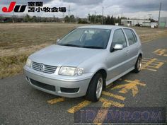 a silver car is parked on the side of the road in front of an empty field