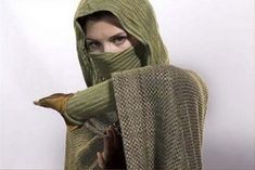 a woman wearing a green knitted shawl and holding her hands under her face