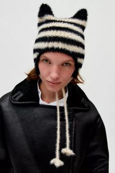 a woman wearing a black and white cat hat with pom - pom on it