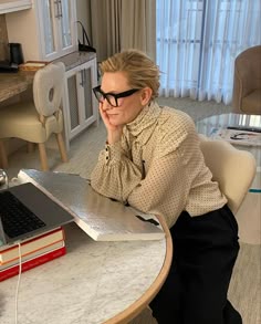 a woman sitting at a table in front of a laptop computer
