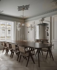 a dining room table and chairs in front of a large window with an ornate chandelier hanging from the ceiling