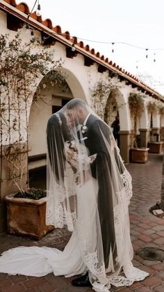 a bride and groom kissing in front of an archway