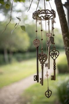 an old key wind chime hanging from a tree in front of a park path