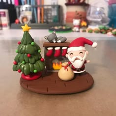 a santa clause figurine sitting on top of a table next to a christmas tree