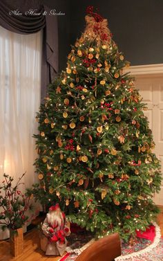 a decorated christmas tree in the corner of a living room with red and gold ornaments