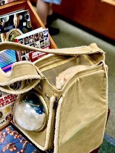 an open bag sitting on top of a wooden table next to a book case and magazine