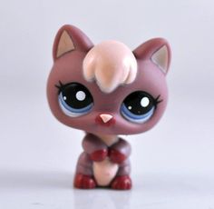 a close up of a small toy cat on a white surface with a gray background