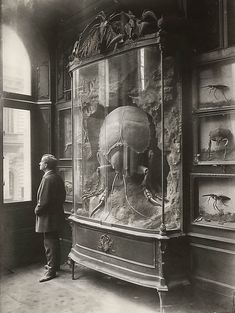 an old black and white photo of a man looking at art on display