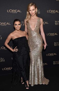 two women standing next to each other on a red carpet