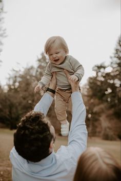 a man holding a baby up in the air