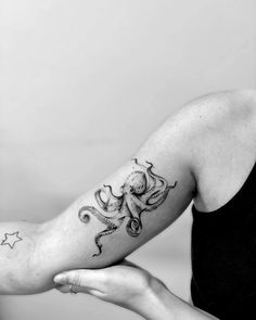 black and white photo of an octopus tattoo on the right arm with stars around it