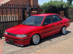 a red car parked in front of a gate
