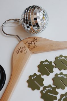 wooden clothes hanger with personalized name tags and disco ball on it next to other items