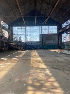 an empty warehouse with lots of windows and graffiti on the walls in front of it