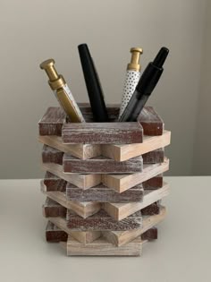 a stack of wooden blocks with pens and pencils in them