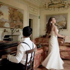 a woman in a wedding dress standing next to a man sitting at a table with a piano