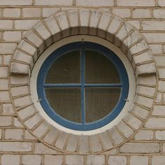a round window on the side of a brick building with blue trim and circular windows