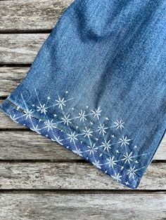 the back side of a pair of jeans with white daisies on them, sitting on a wooden surface