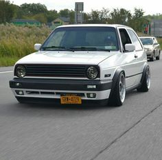two white cars driving down the road next to each other in front of another car