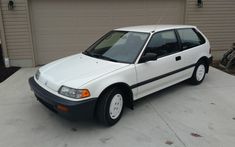a white car parked in front of a garage