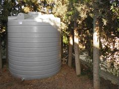a large gray water tank next to some trees