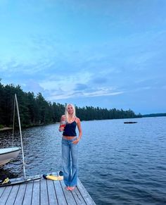 a woman standing on a dock next to a body of water