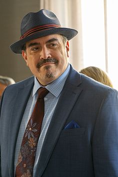 a man wearing a suit and tie with a hat